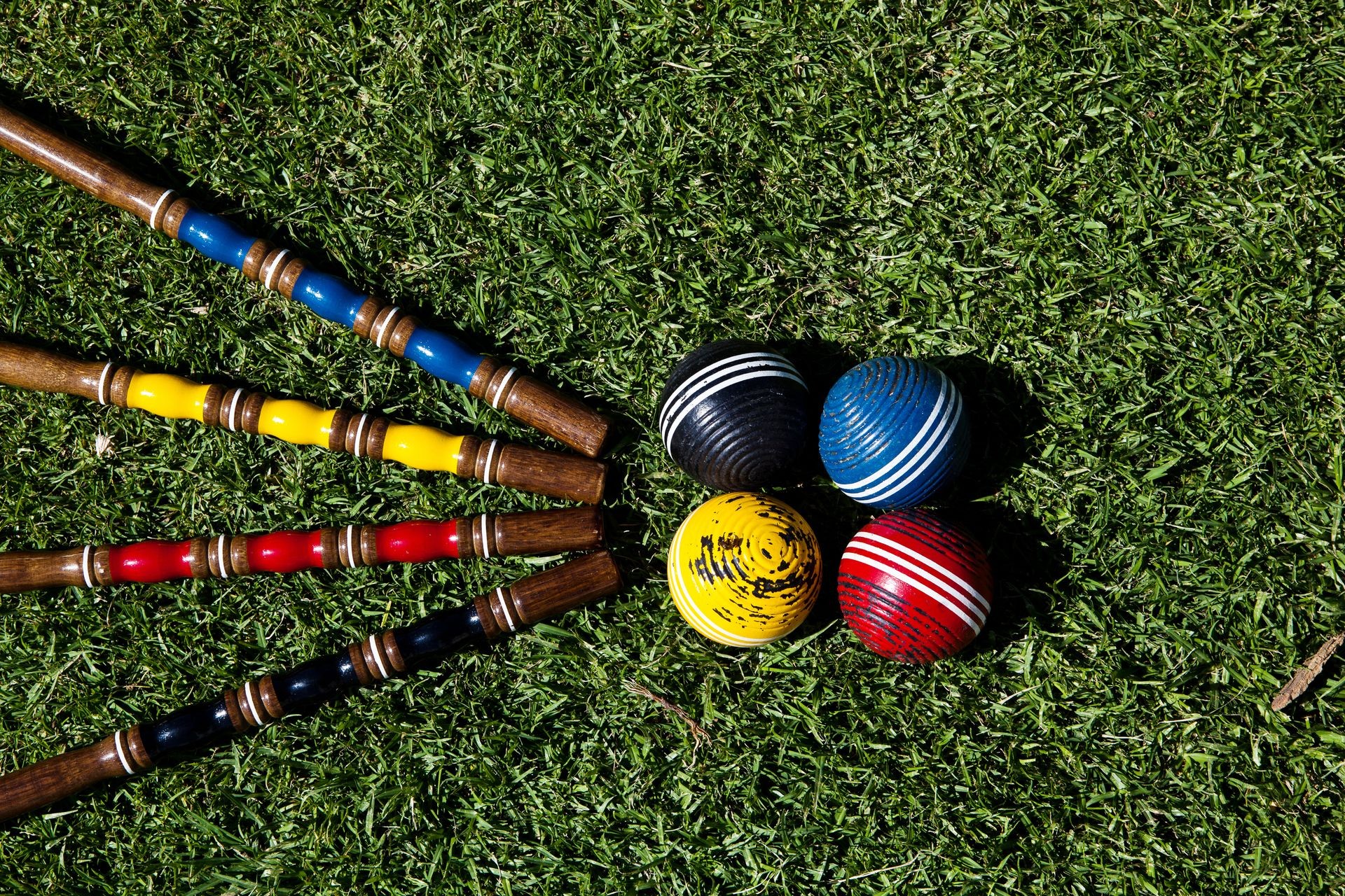 Croquet set and colorfull balls sit on the ground.