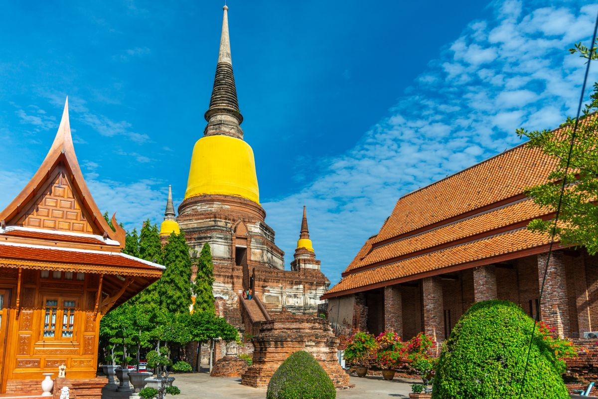 Old brick pagoda with surrounding building in Thai temple in Ayuddhaya, the UNESCO World heritage city, Thailand, under cloudy blue sky