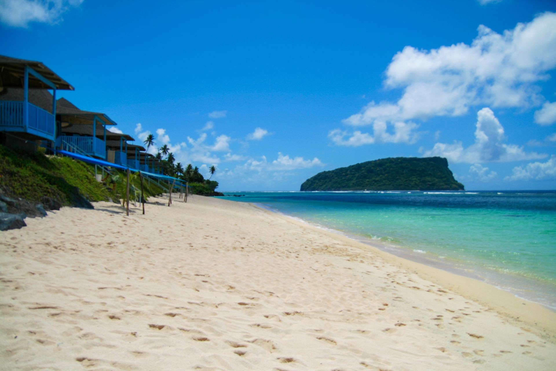 Tropical paradise polynesian style beachfront villas, beach resort on golden sand at Upolu Island Lalomenu beach, Nu’utele island at ocean horizon, Western Samoa, Polynesia