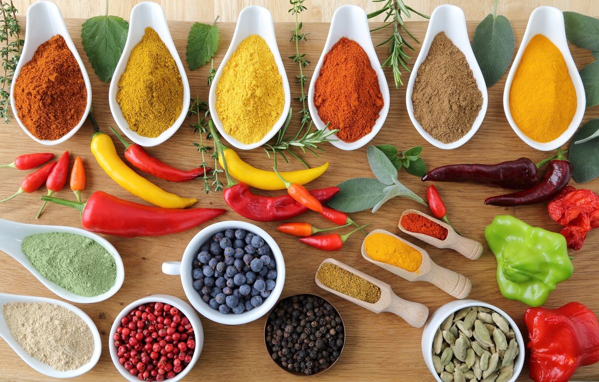 Aromatic and colorful spices in ceramic containers on a wooden background.