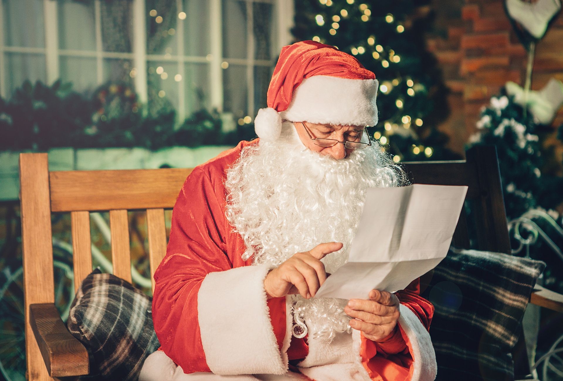 Santa claus read letter from children over living room, christmas tree. Happy santa writing list with a quill at home.Holidays, childhood and people concept 