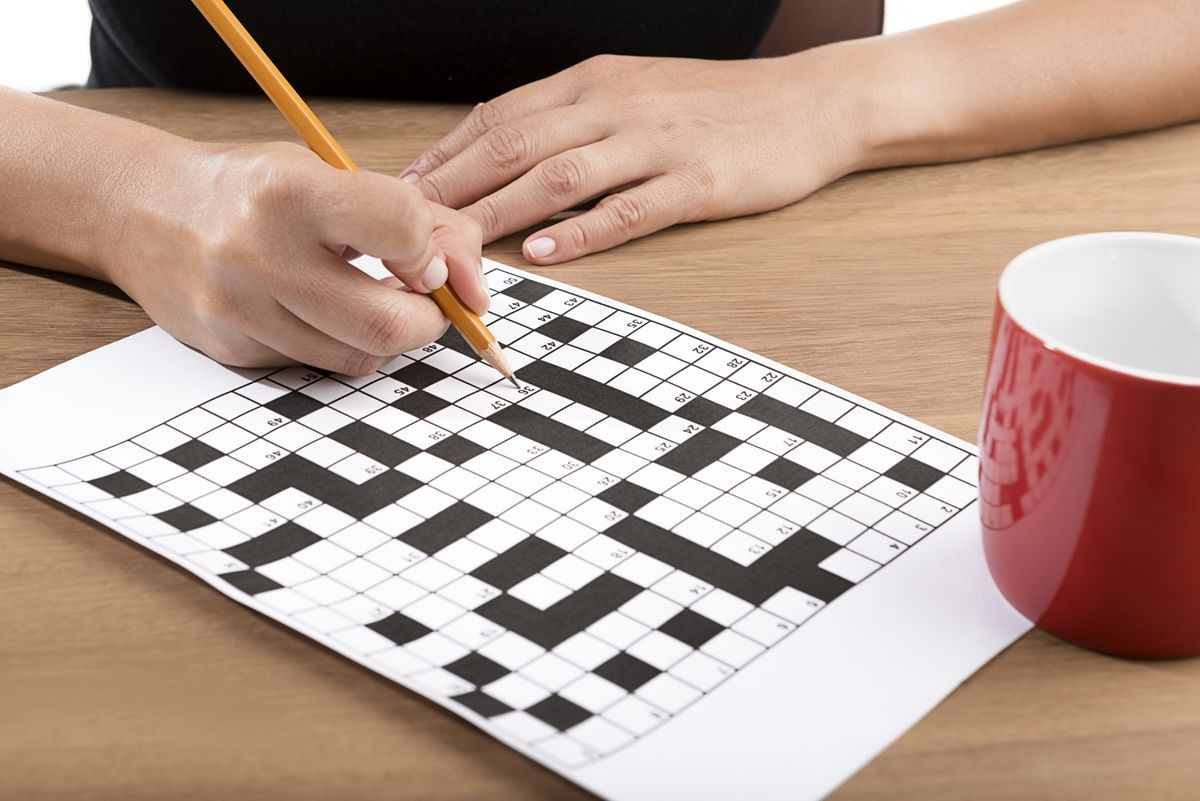 Solving crossword puzzle with yellow pencil.   
