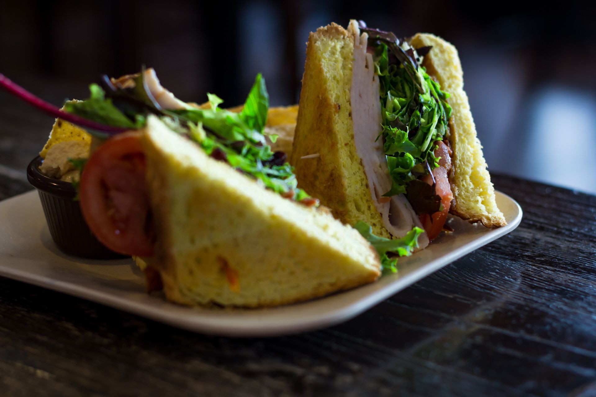 Turkey BLT sandwich on texas toast with sesame seed chips and hummus