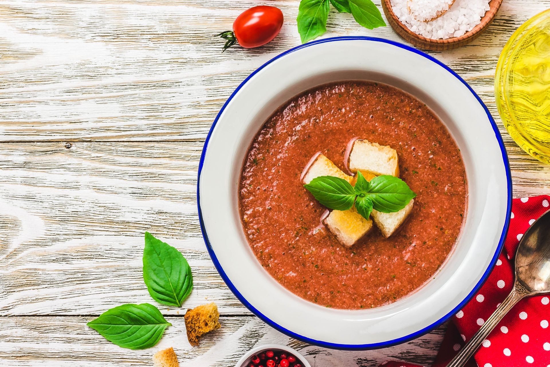 Healthy summer cold tomato soup, gazpacho with basil and garlic bread. Top view, space for text.