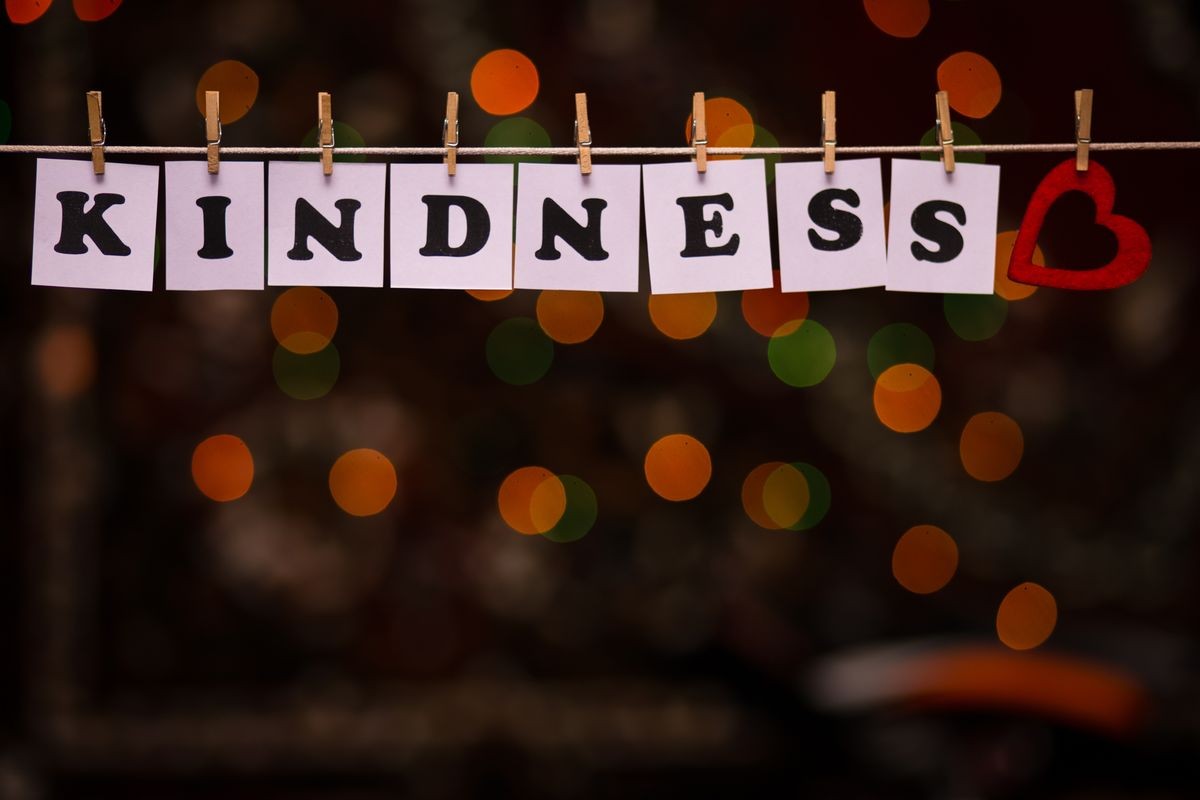 Kindness text on papers with clothespins with garland bokeh on background. The word "Kindness". Kindness concept