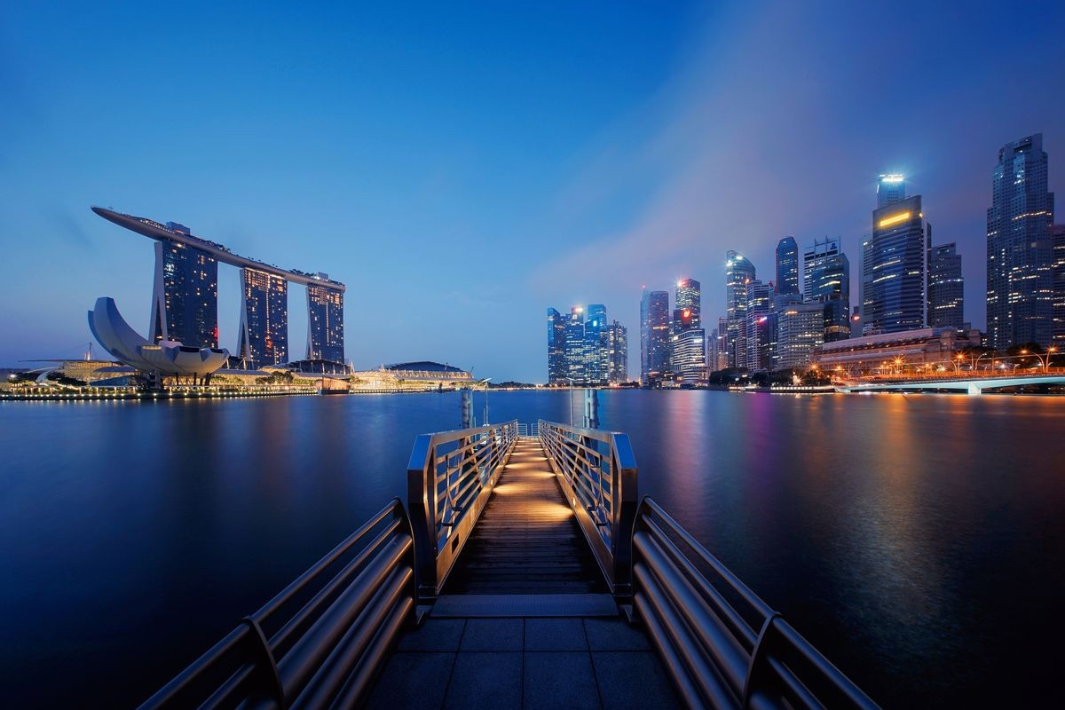 Pier in Downtown Singapore city in Marina Bay area. Financial district and skyscraper buildings at night.