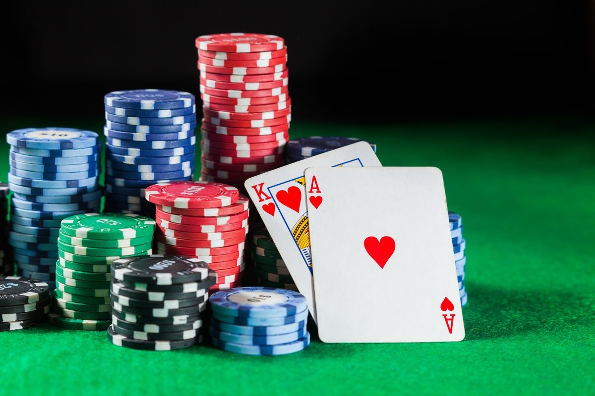 The poker chips stack with two cards king and ACE. On a green background.