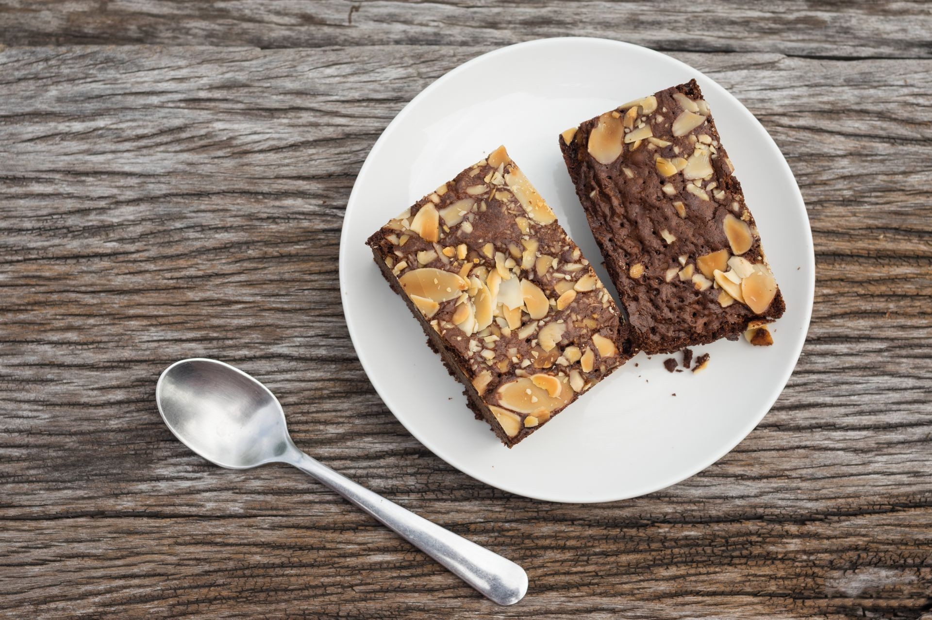 Chocolate brownies topping with almonds slices on wooden table.