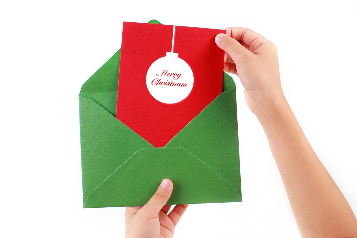 Green envelope with red Christmas invitation & greeting card on white background