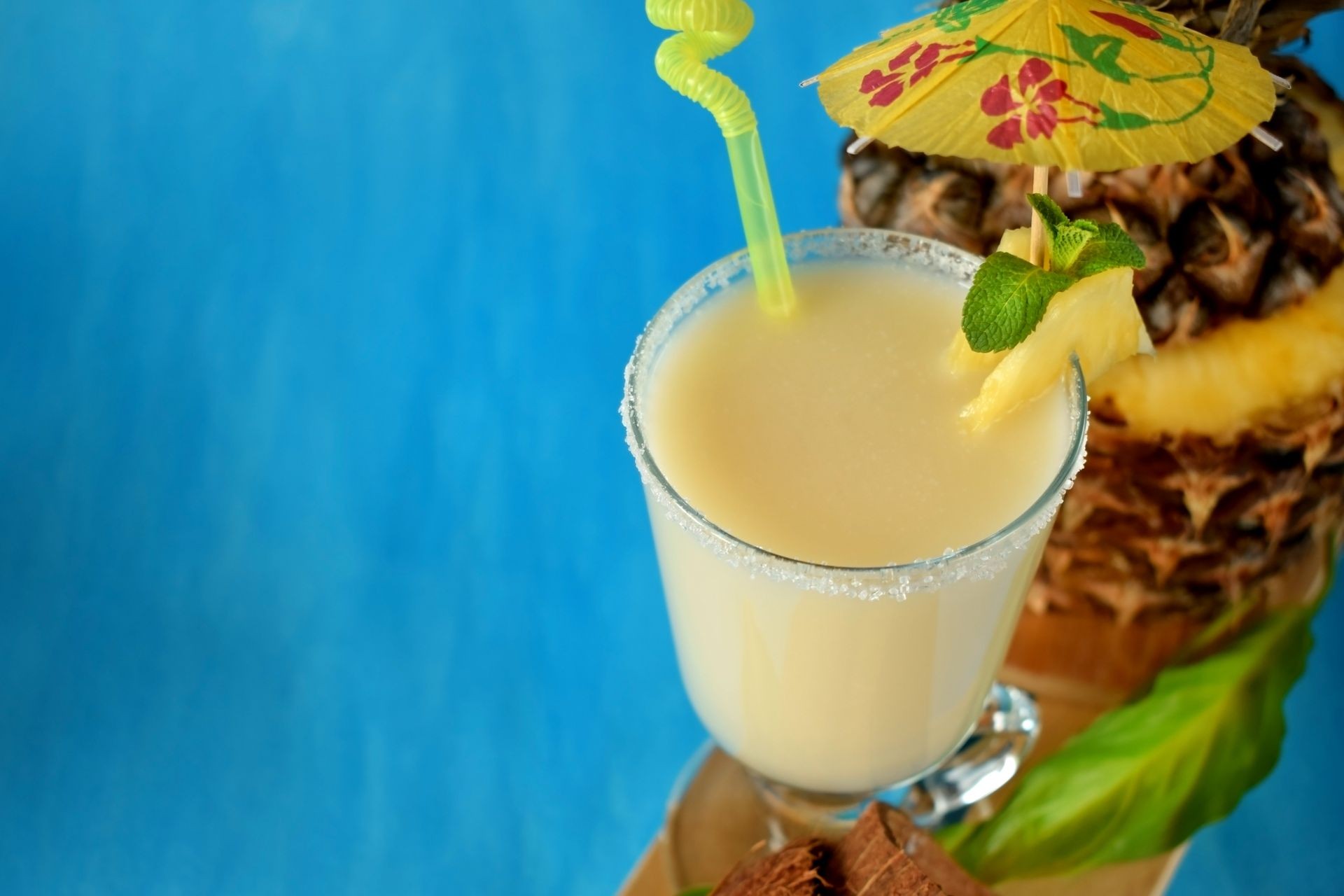 Milk fruit cocktail in an Irish mug decorated with an umbrella and a straw on blue background. Copy space