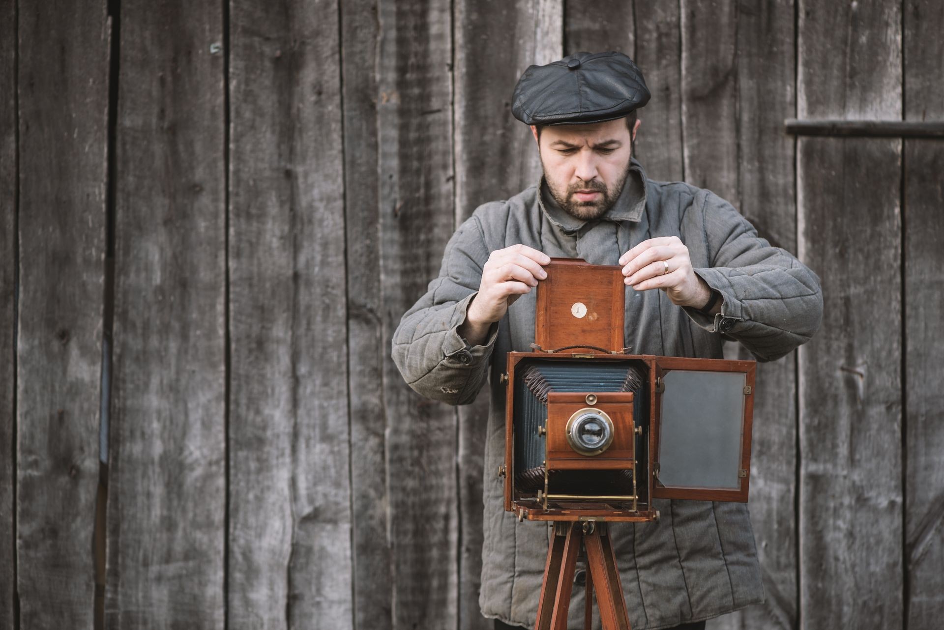 Photographer prepares for shooting and inserts film holder into retro large format camera. Concept - photography of the 1930s-1950s.