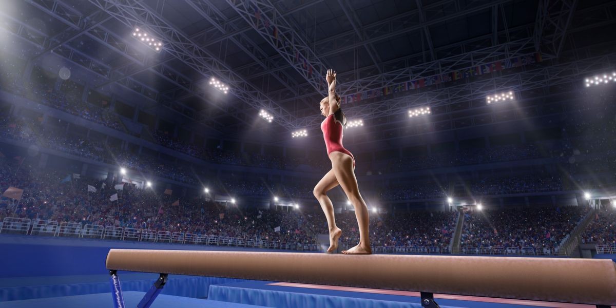 Female athlete doing a complicated exciting trick on gymnastics balance beam in a professional gym. Girl perform stunt in bright sports clothes