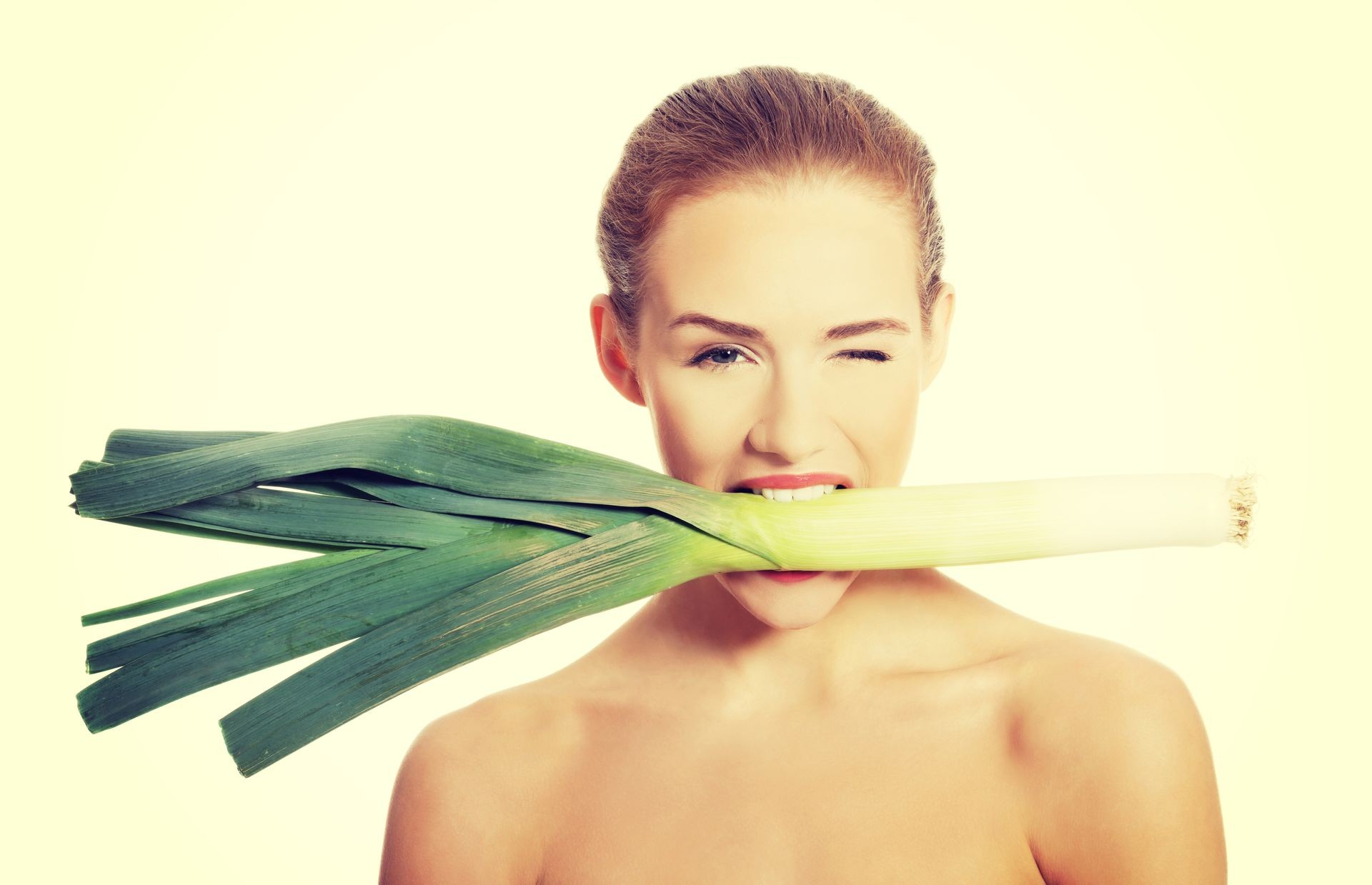 Beautiful woman with fresh green leek in mouth