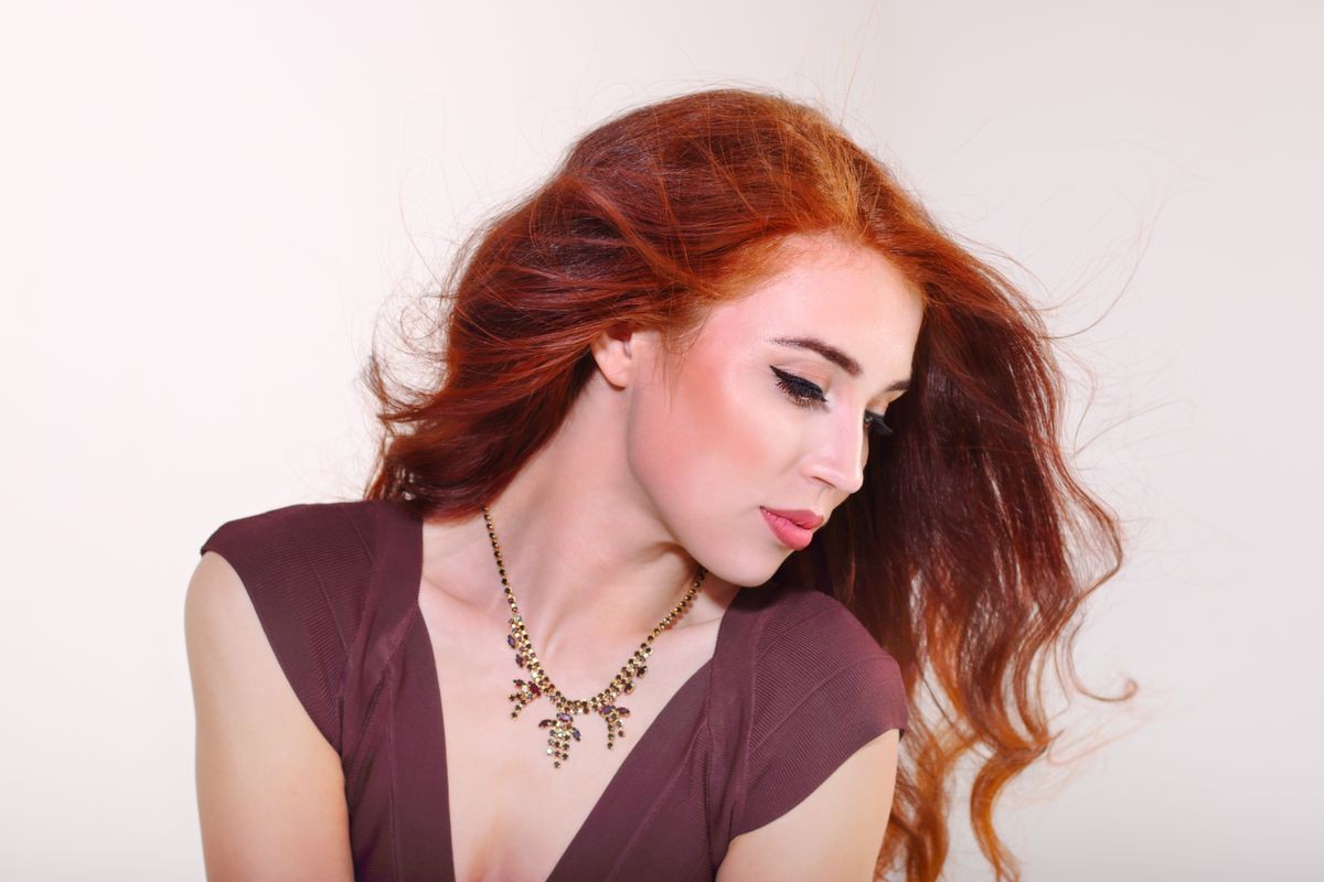 Closeup beautiful young girl with red hair posing in brown dress