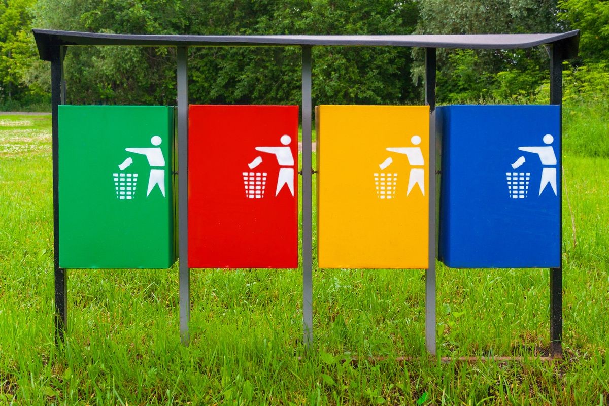 Four colors recycle bins or trash can, against a background of city park