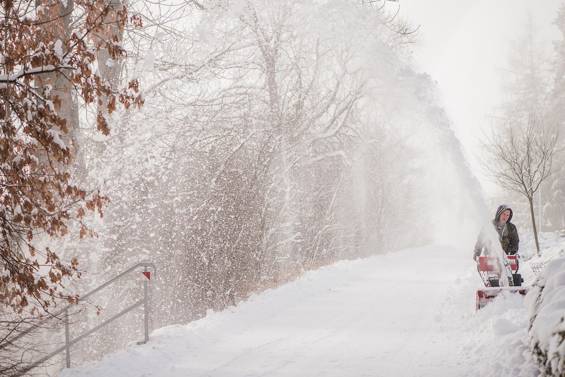 hard working man clearing snow with snow blower  after exteme heavy snow storm fall in sub zero freezing temperatures 