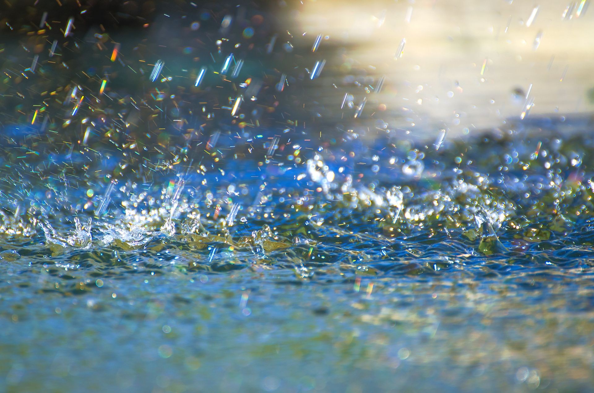 Drops of heavy rain on water. Drops of heavy rain on sidewalk surface. Rain water on the surface of the flood the sidewalk on the city street. Detail of rain drops in a storm on a road