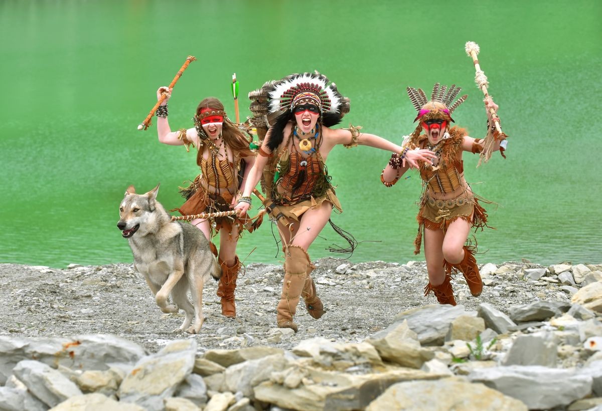 A group of three young girls get dress as native American 
Indians. They attack with their grey wolf by their side.
Behind them a green lake in the middle of a stone quarry.