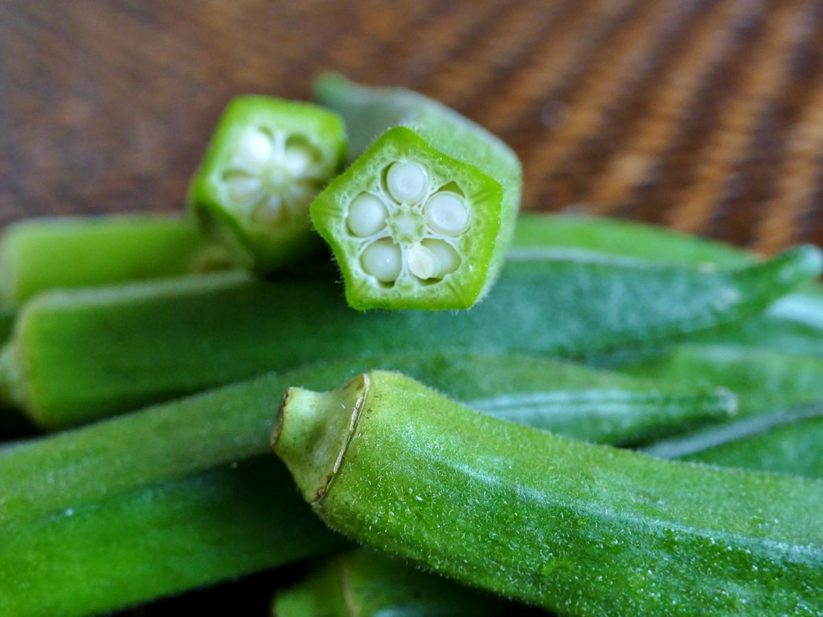 close up photo of okra or ladies finger which is popular vegetable in Japanese food.  piling of green okra in wooden container