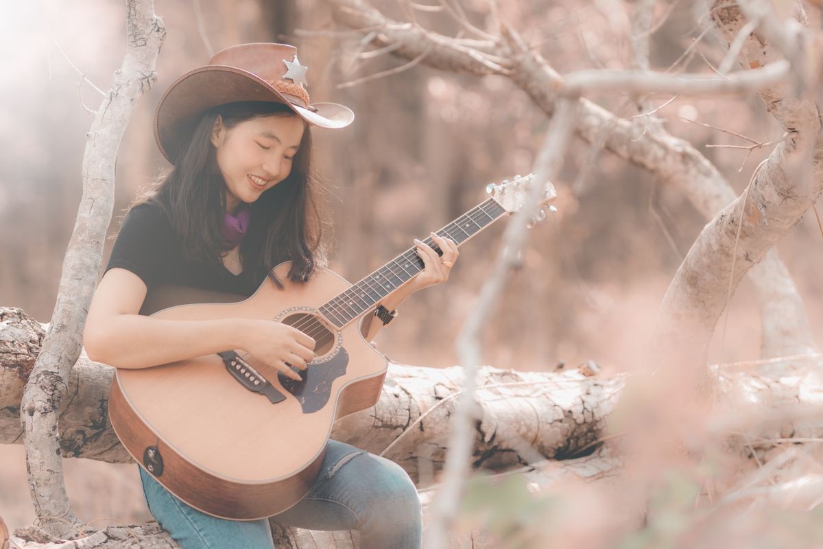 Asia country music woman playing the guitar in the forest with relax and happy in free time,use for web cover design,background.