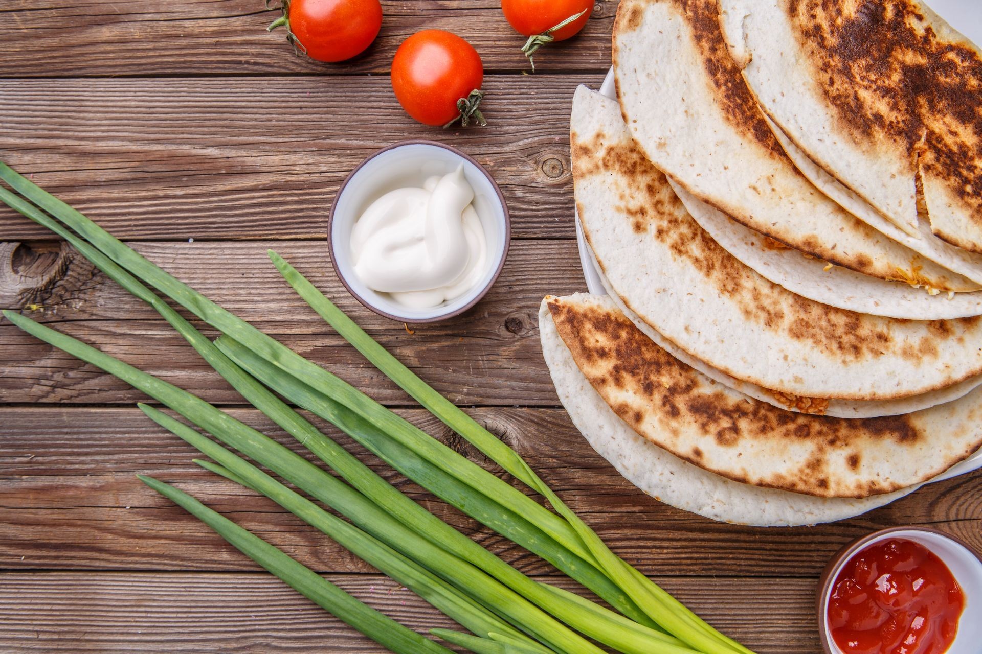 Quesadilla with chicken ,green onions, with dressing on wooden table