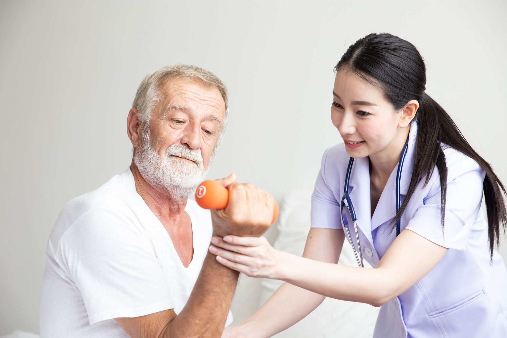 Senior retirement man doing dumbbell fitness training with  physiotherapist