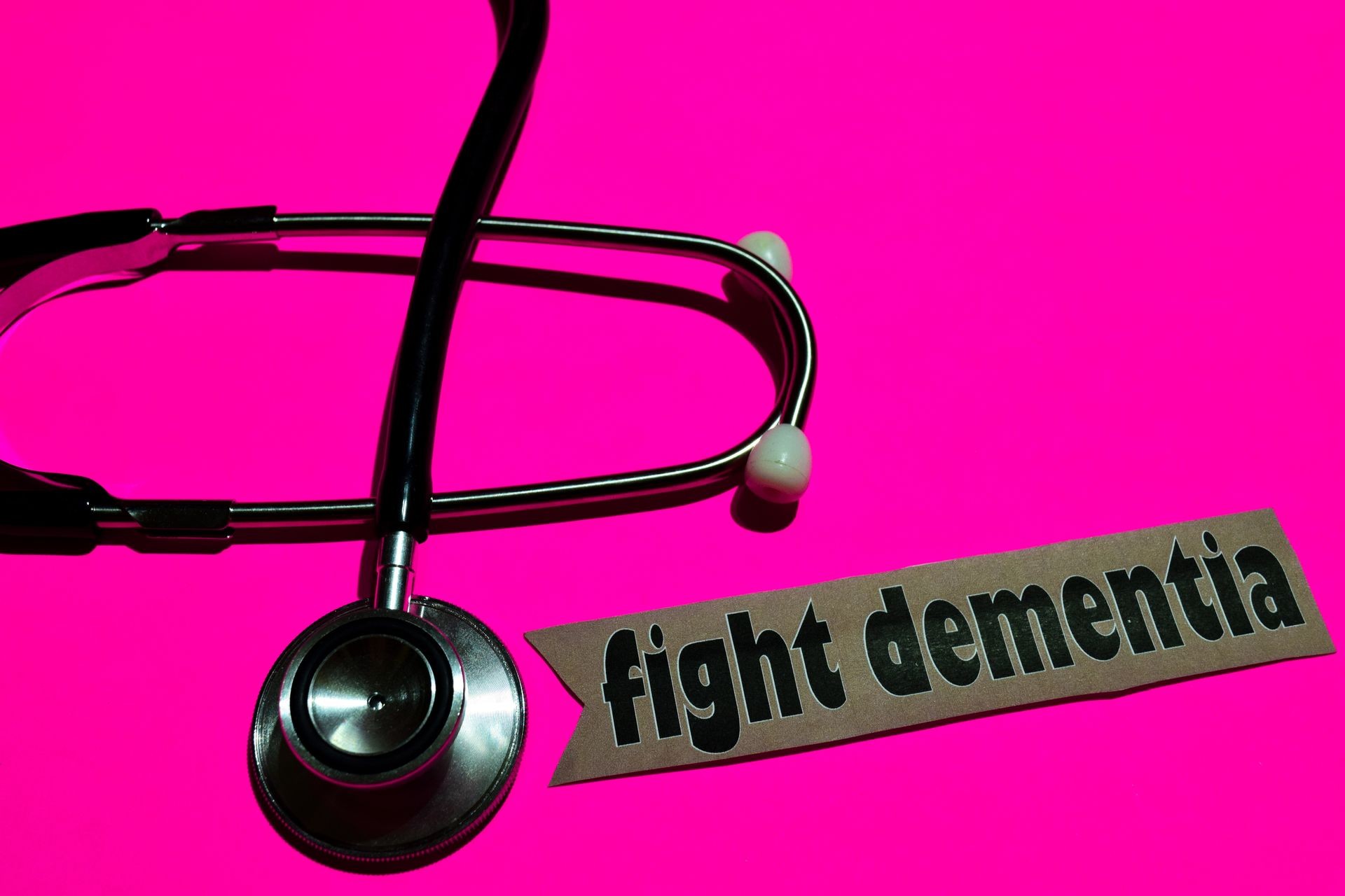 Fight dementia on the paper with healthcare concept Inspiration. stethoscope on pink bakcground