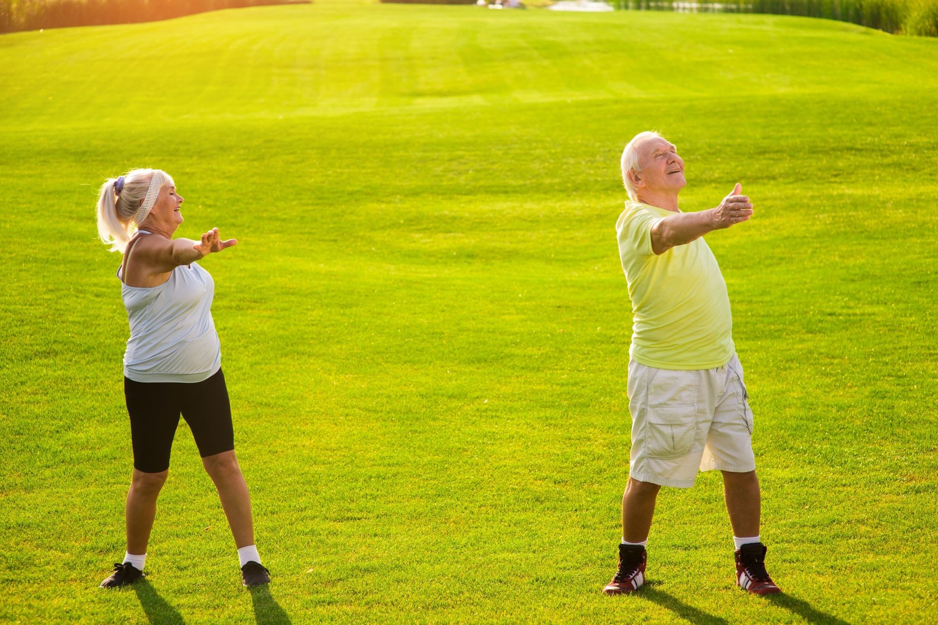 Elderly couple does exercise. Woman with man on meadow. Health is priceless. Fitness as a lifestyle.