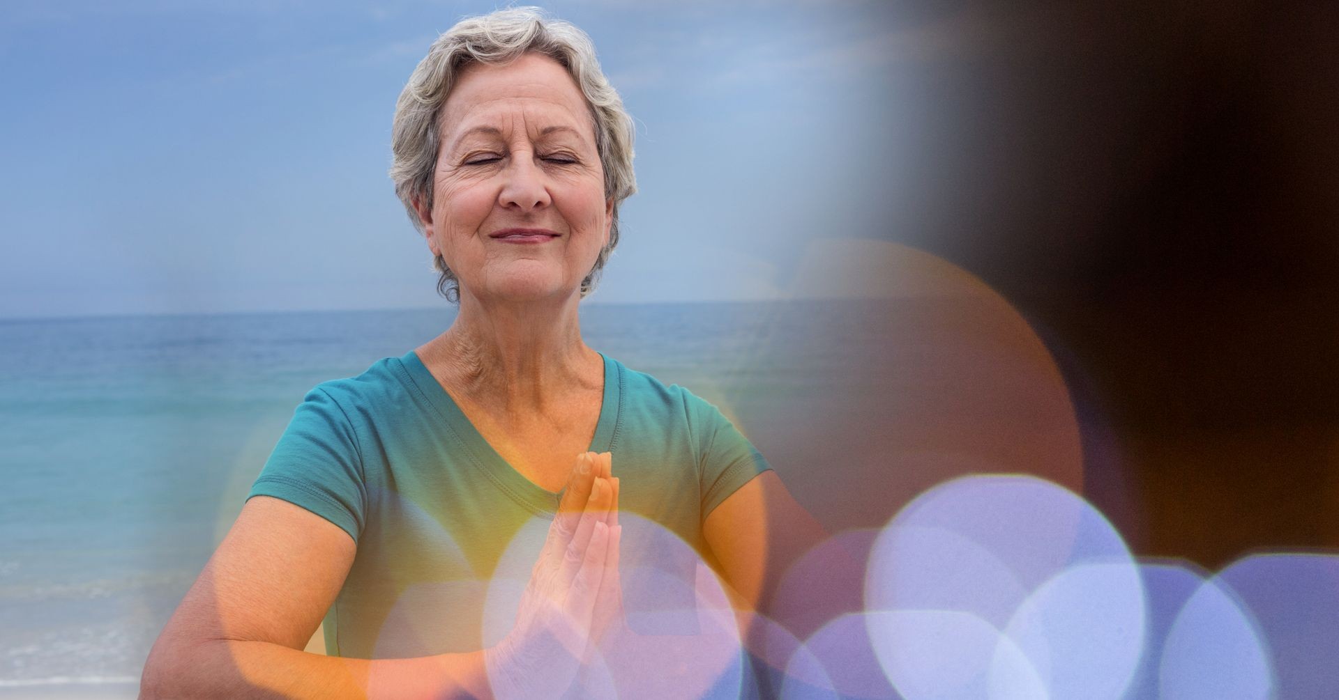 Senior women meditating on beach against sky